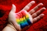 Image of a hand painted with a rainbow flag and a heart