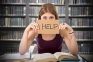 Image of a woman in a library holding up a sign that says help