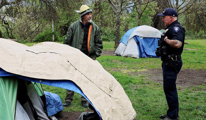 Officer Tim Artoff tells an unhoused man that he needs to leave the park in two hours in Grants Pass, Ore., April 18, 2024.